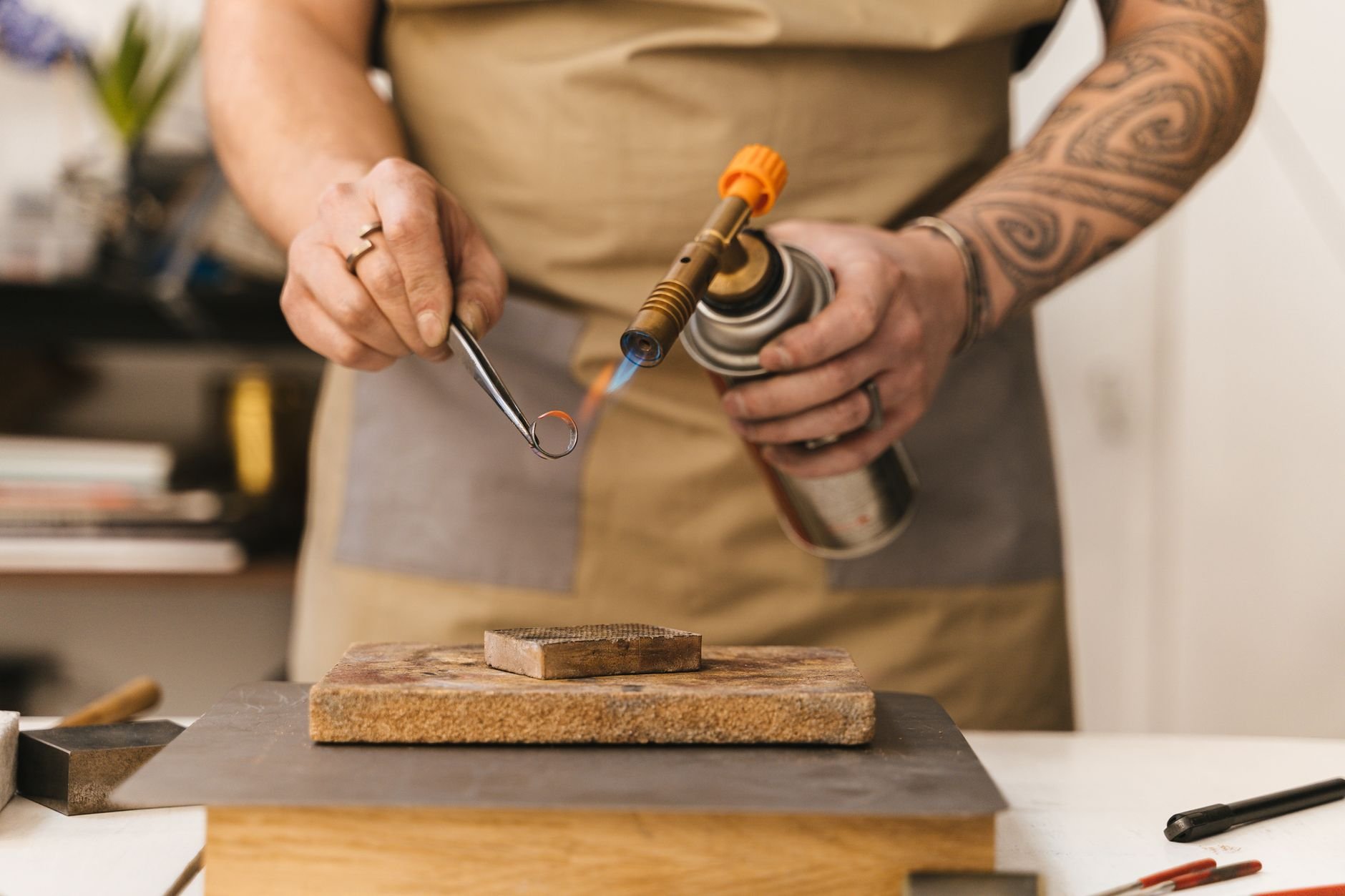 Jeweler using a torch to craft a ring in a workshop, showcasing artisanal skills.